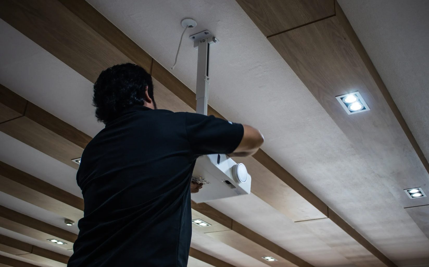 An ASC technician installing a ceiling-mounted AV system